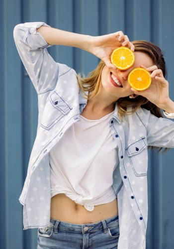 Smiling woman holding two grapefruits in hands on a blue background